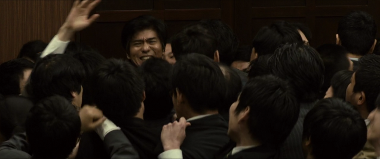 피해자가 중태인 교통사고 가해자의 실명을 비공개하자 기자들이 경찰 간부를 찾아가 항의한다. 이를 막으려 공보관 미카미는 안간힘을 쓴다. / TOHO