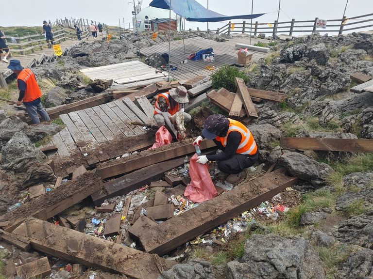22일 제주 한라산 정상 백록담 동능 데크를 철거한 뒤 나온 쓰레기를 작업자들이 수거하는 모습. /연합뉴스