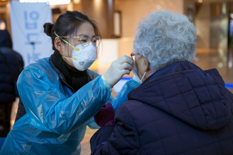 27일 서울의료원 관계자가 이용객에게 마스크를 나눠주며 사용법을 설명하고 있다. /연합뉴스