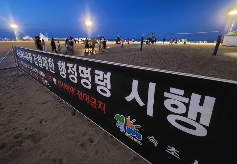 강원 동해안 8개 주요 해수욕장에서 시행 예정인 야간 취식행위 단속을 앞두고 사전 계도 활동이 시작된 지난 18일 속초해수욕장 입구에 집합제한 행정명령에 따른 단속 안내 현수막이 걸려있다. /연합뉴스